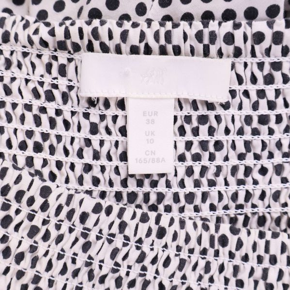 Etikett med storlek EUR 38 på klänning i prickigt tyg