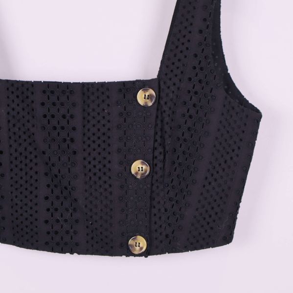 Närbild på tre guldfärgade knappar på svart topp