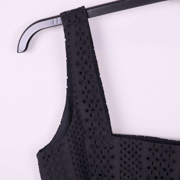 Närbild axelband och broderad struktur på svart topp