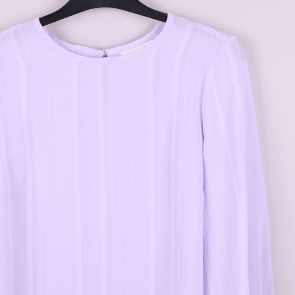 Närbild av axel och halsringning på ljuslila blus