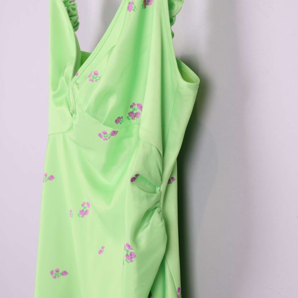 Närbild på sida av ljusgrön klänning med små lila blommor