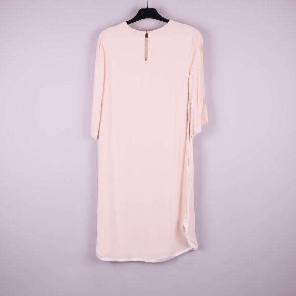 Baksidan av ljusbeige klänning med knapp i nacken