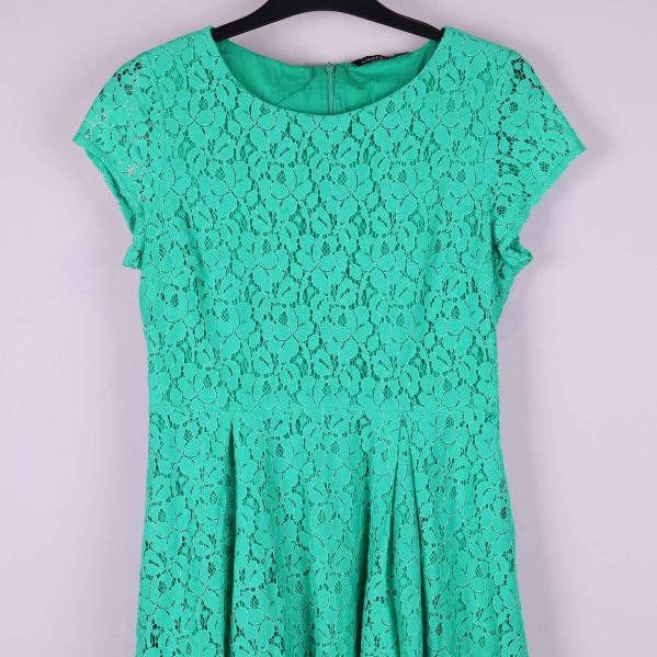 Detalj av överdelen på grön klänning med spetsstruktur