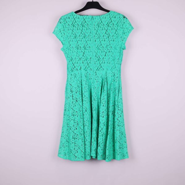 Grön spetsklänning med rund hals och korta ärmar hängande på galge, sedd bakifrån