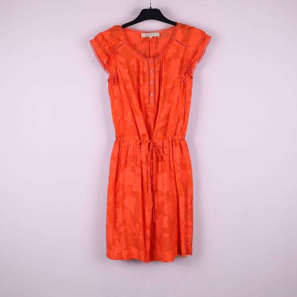 Kort orange klänning med strukturmönster hänger på galge
