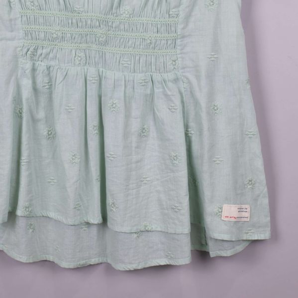 Närbild på nedre delen av blus med tyglager och etikett