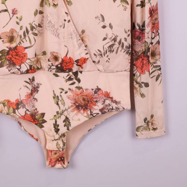 Ärm och sida av blommig beigefärgad body