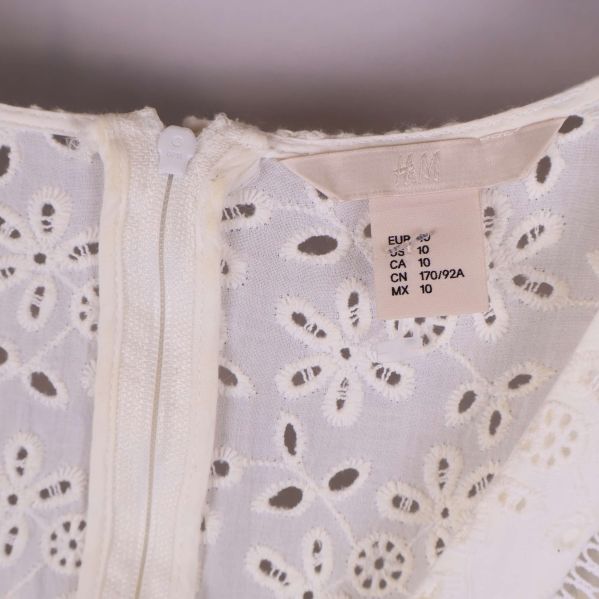 Närbild på storleksetikett och dragkedja vid halsen på klänningen