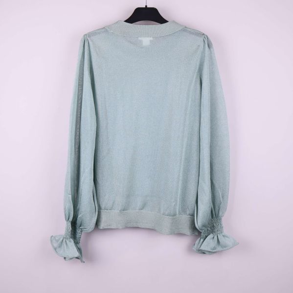 Ljusgrön tröja bakifrån med volangdetaljer vid ärmslut