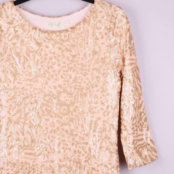 Närbild på övre del av paljettklänning med mönster och halsringning