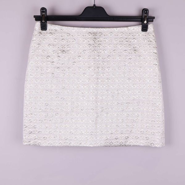 Kort kjol i ljust tyg med strukturmönster framifrån