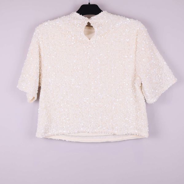 Paljettopp bakifrån med knappdetalj och rundad öppning