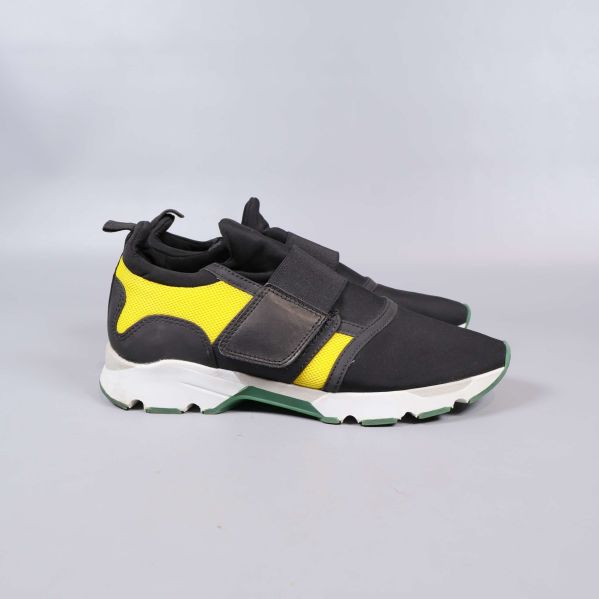 Sneakers sedd från sidan, gula meshpaneler synliga