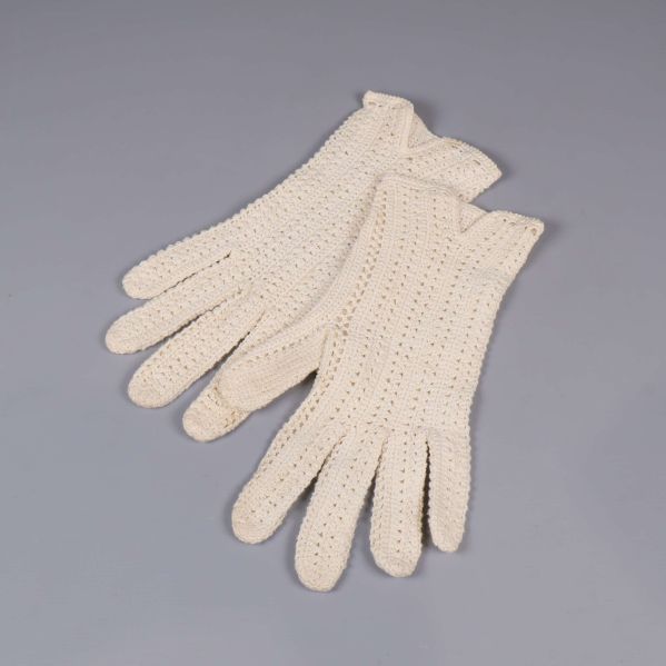 Virkade naturvita handskar placerade på ljus bakgrund