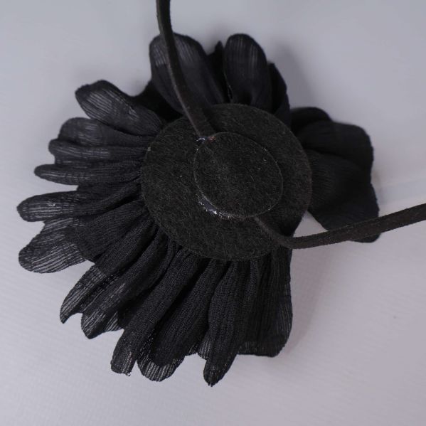 Baksida av tygblomma med rund fästplatta och band