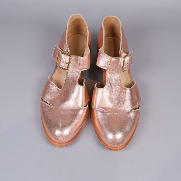 Ovandelen av par metallicfärgade sandaler med spännen