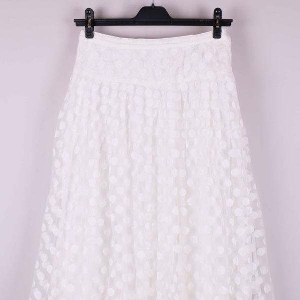 Övre delen av vit kjol med tydligt prickigt mönster