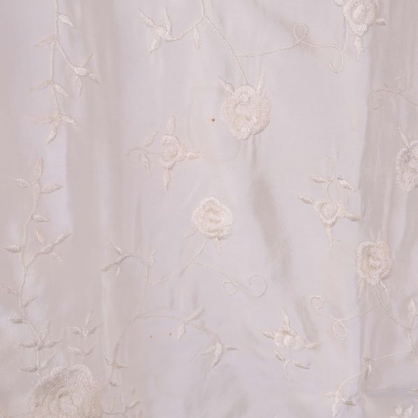 Närbild på broderade blommor i vitt tyg