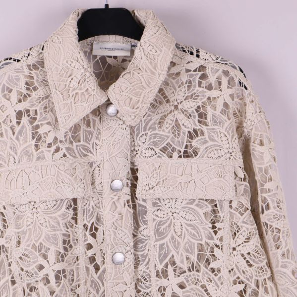 Närbild på krage och fickdetalj på spetsjacka