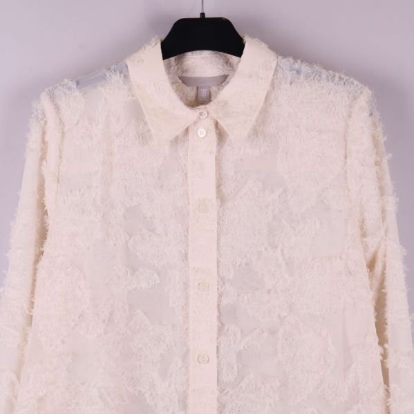 Närbild på krage och knäppning av beige skjorta