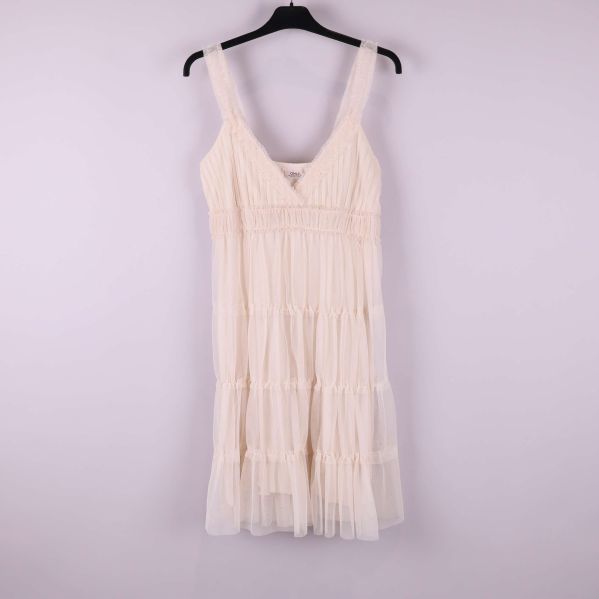 Ljus volangklänning på galge fotograferad framifrån