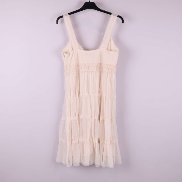 Ljus volangklänning på galge fotograferad bakifrån