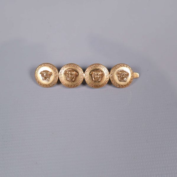 Hårspänne i guld med fyra dekorerade runda emblem