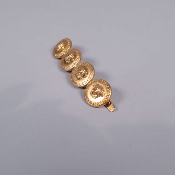 Hårspänne i vinkel som visar guldfärgade emblem