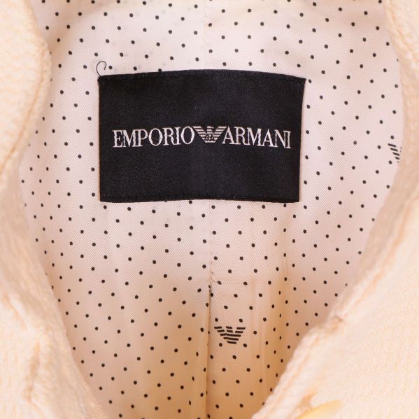 Närbild på Emporio Armani-märkesetikett mot prickigt foder