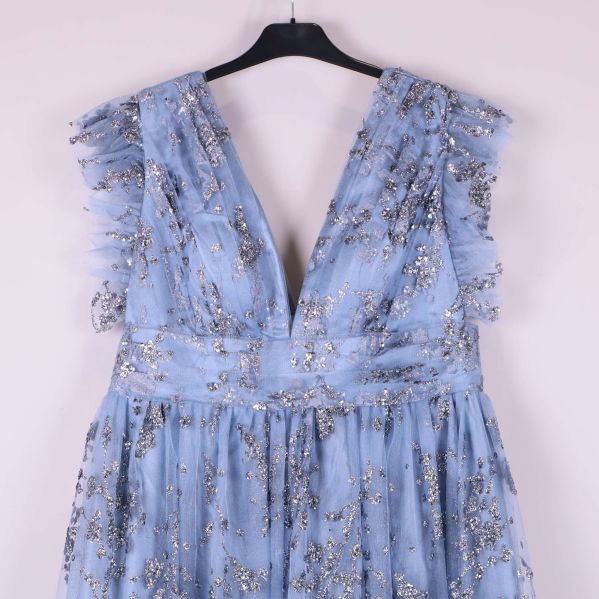 Närbild av djup v-ringning och volang på axlarna