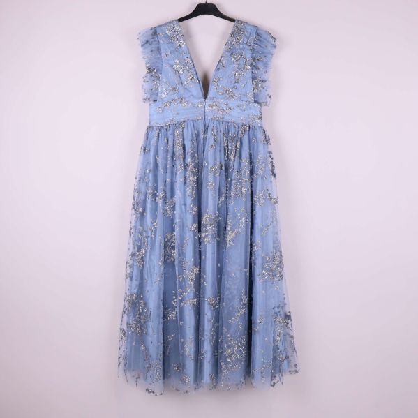 Ljusblå klänning med glitterdetaljer bakifrån på galge