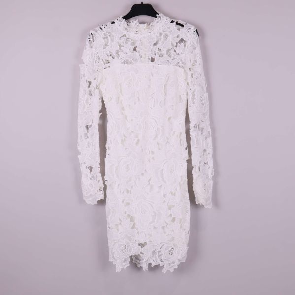 Vit spetsklänning med lång ärm framifrån mot ljus bakgrund