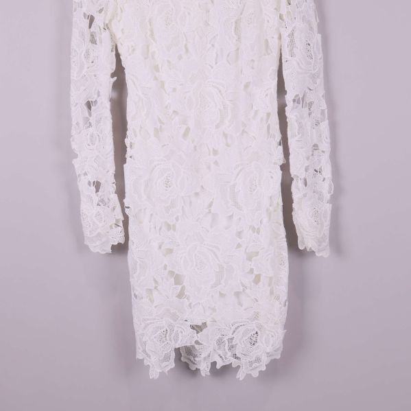 Närbild på underdelen av vit spetsklänning