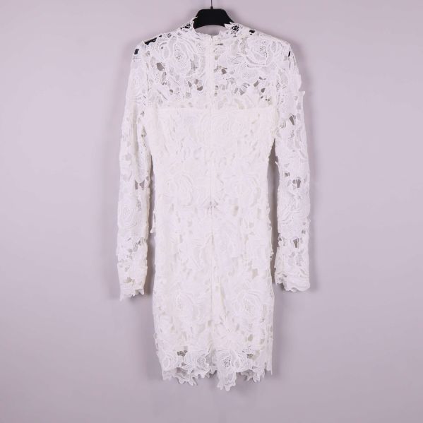 Vit spetsklänning med lång ärm bakifrån mot ljus bakgrund