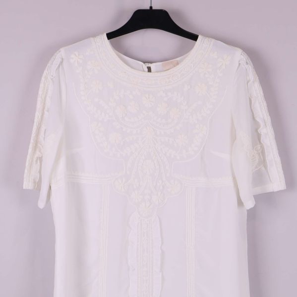 Övre framdel av klänning med spetsmönster och detaljer