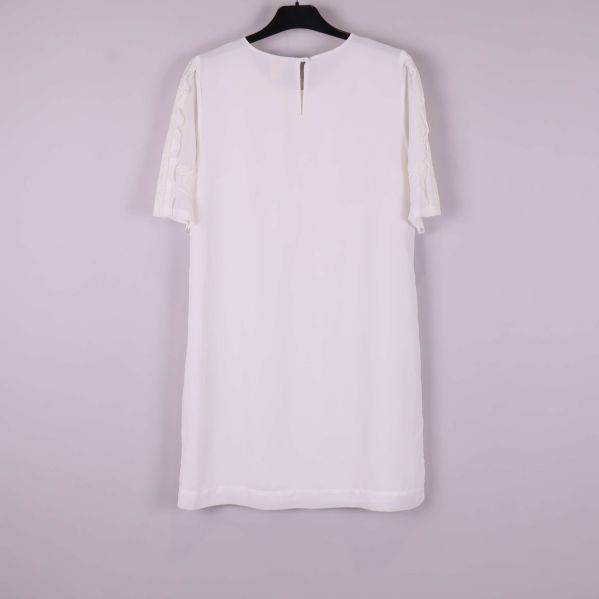 Baksida av vit klänning med knapp i nacken