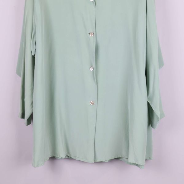 Nedre del av skjortan med fåll och knappdetaljer