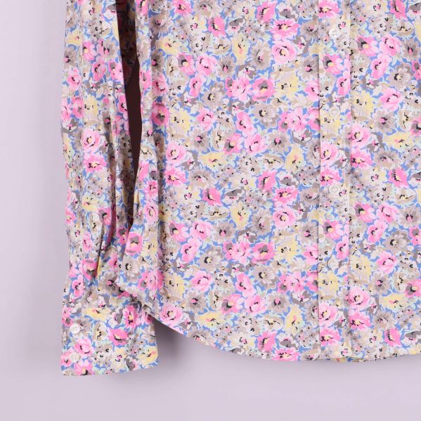 Detalj på skjortans ärm och knappslejf med blommigt mönster