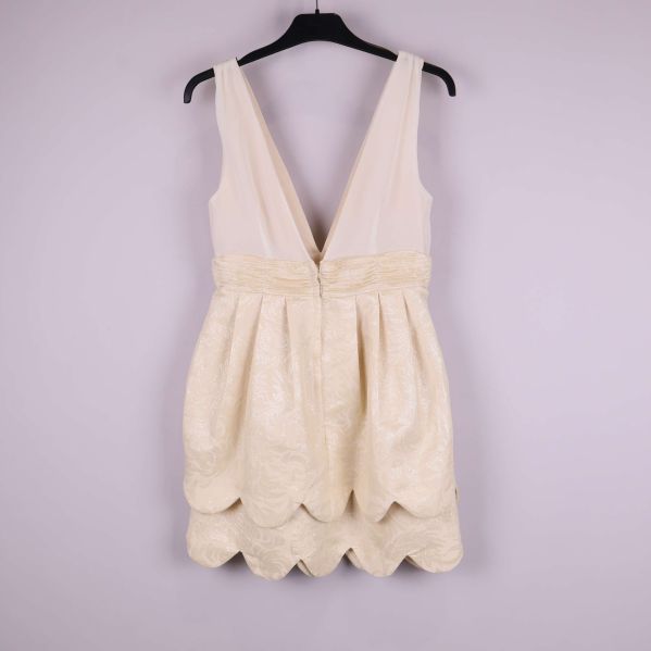 Baksida av ljus klänning med dragkedja och scallop-kant