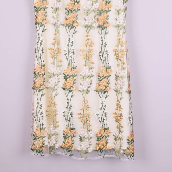 Nederkant av klänning i vitt med blombroderier