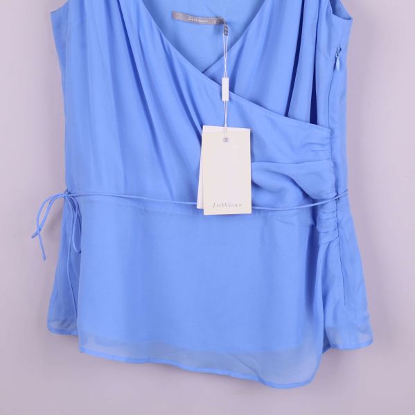 Nederdel av ljusblå topp med knytband i sidan