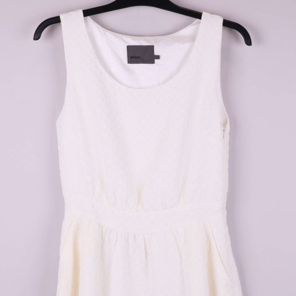 Övre del av vit ärmlös klänning med struktur