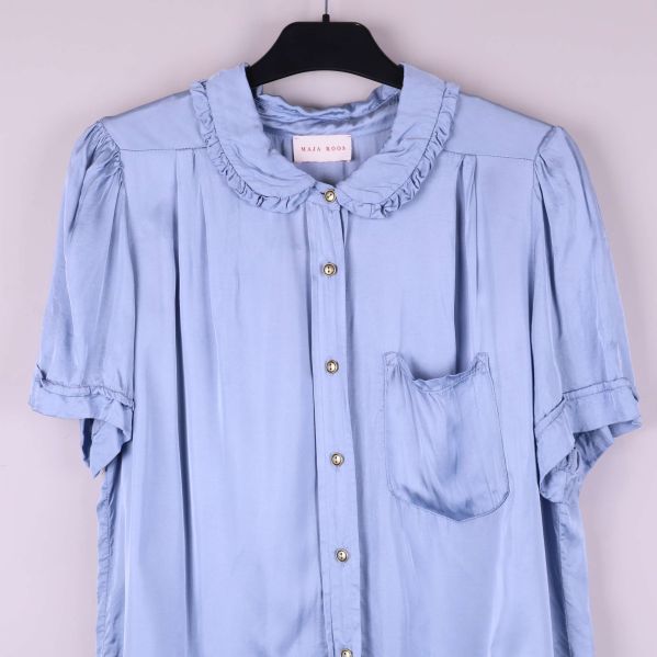 Närbild på blusens bröstparti och volangkrage