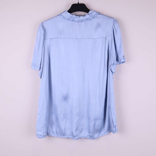Baksida av ljusblå blus med kort ärm och volangkrage