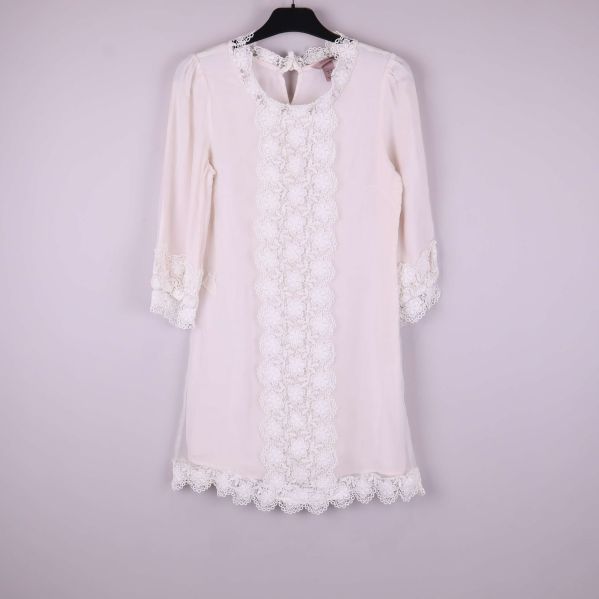 Vit klänning med spets i helfigur framifrån på galge