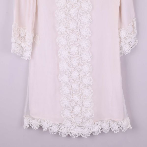 Närbild på klänningens spetsdetaljer vid nederkant och ärmslut