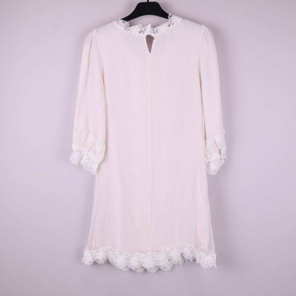 Vit klänning med spets i helfigur bakifrån på galge