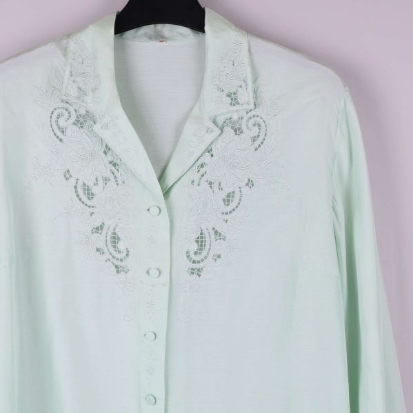 Närbild på krage och bröst med vita broderier