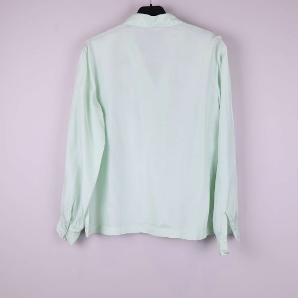 Blusens baksida i ljusgrön färg visas upp