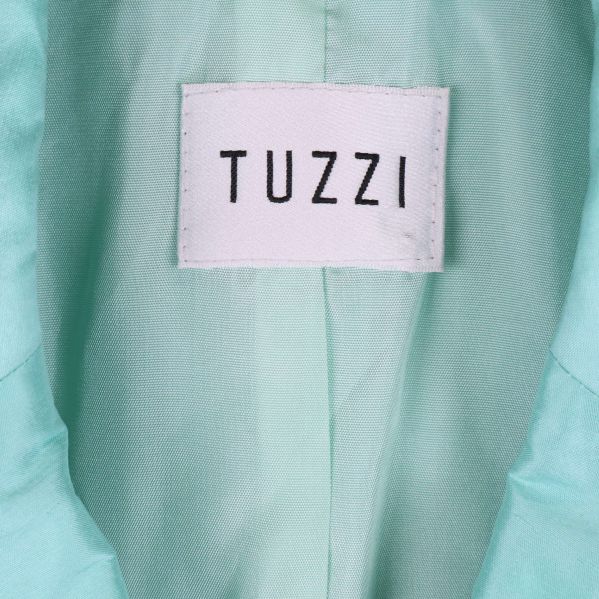Närbild på Tuzzi etikett i ljusblå blazer